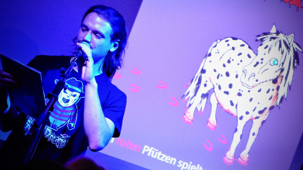 Marien Loha liest an Halloween mit einem Dalmatinerpony im Hintergrund.